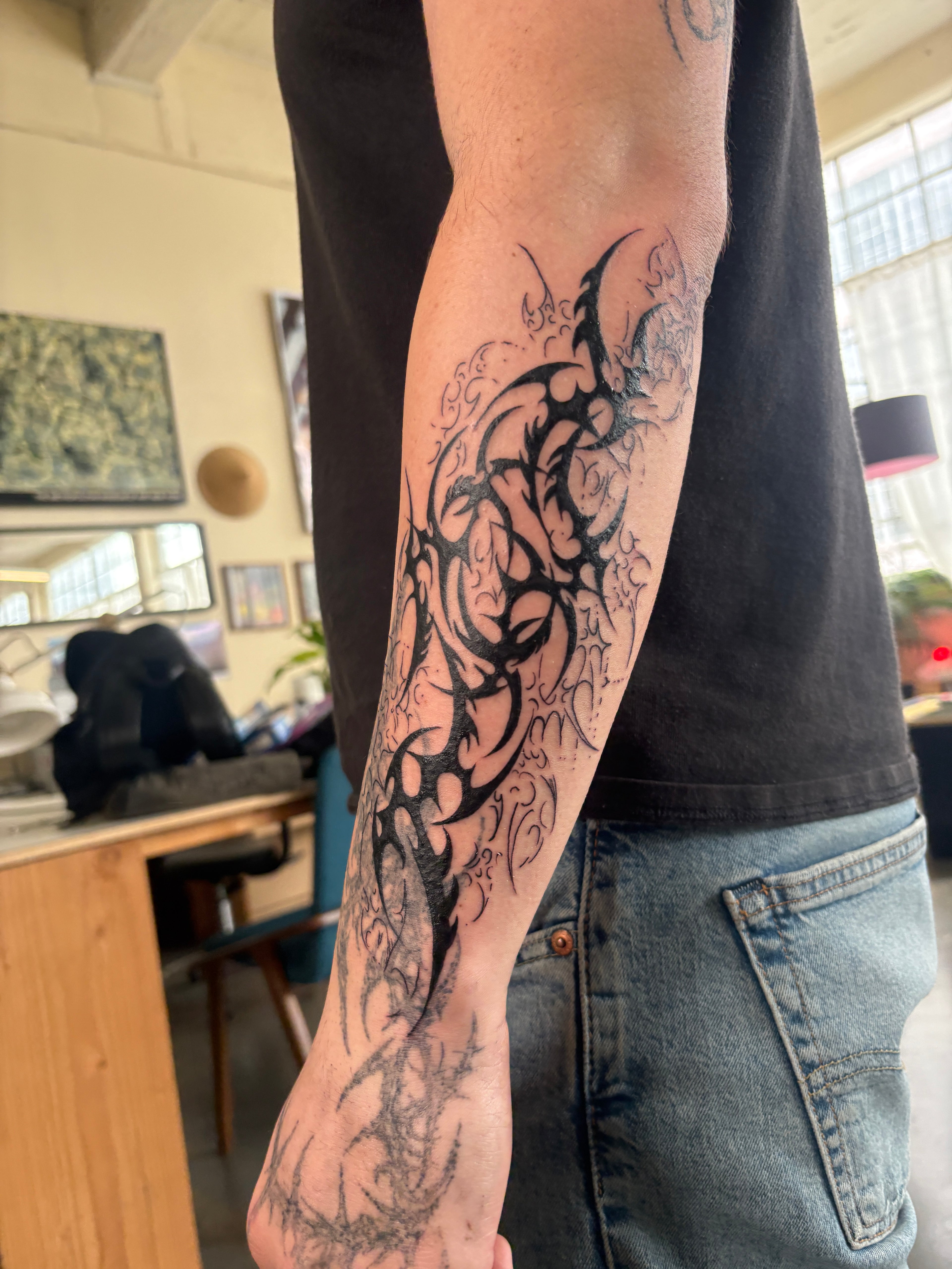 Person's arm with a black tribal cyber sigilism tattoo 