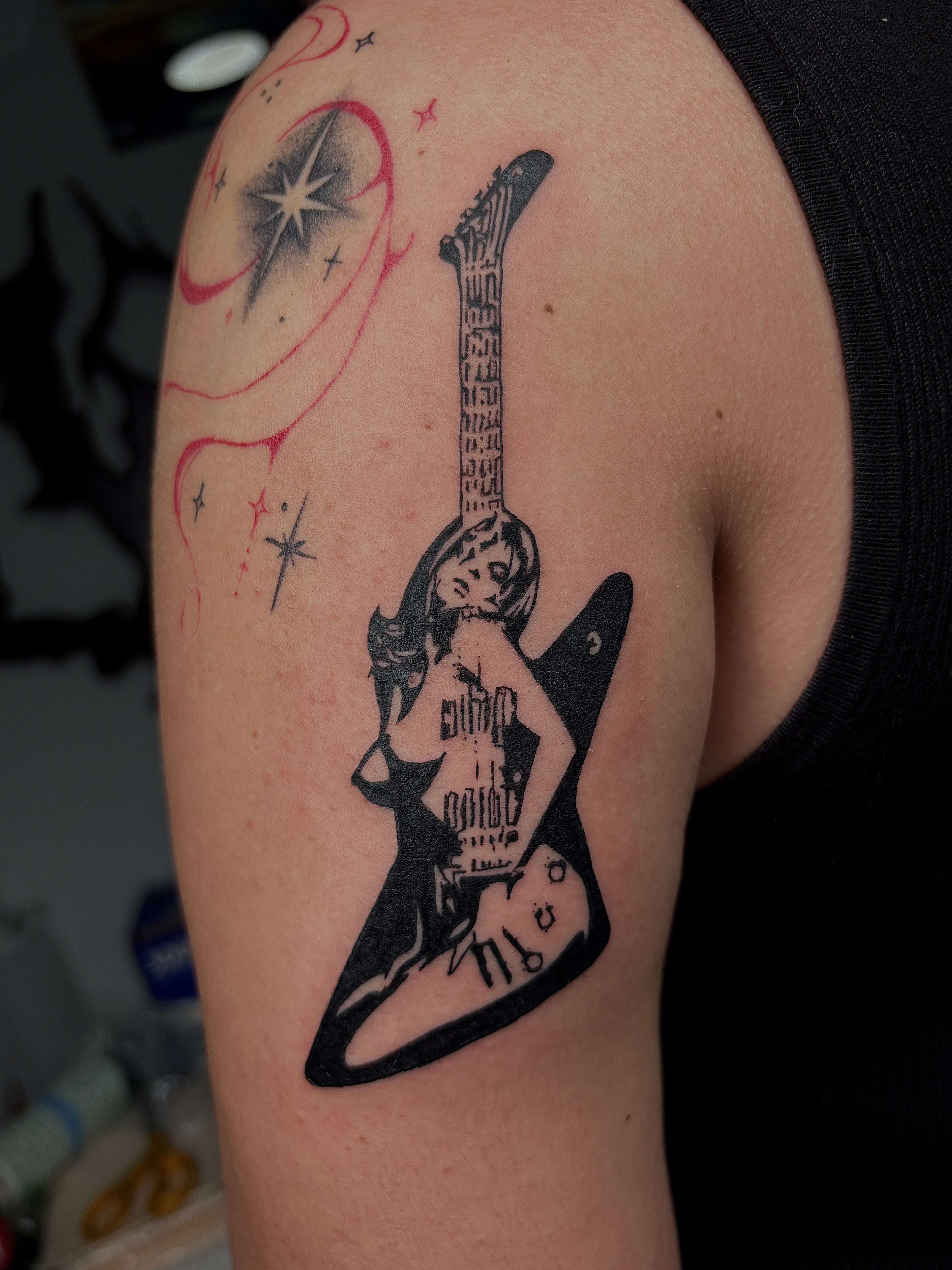 Tattoo of a hysteric glamour guitar on a person's arm 