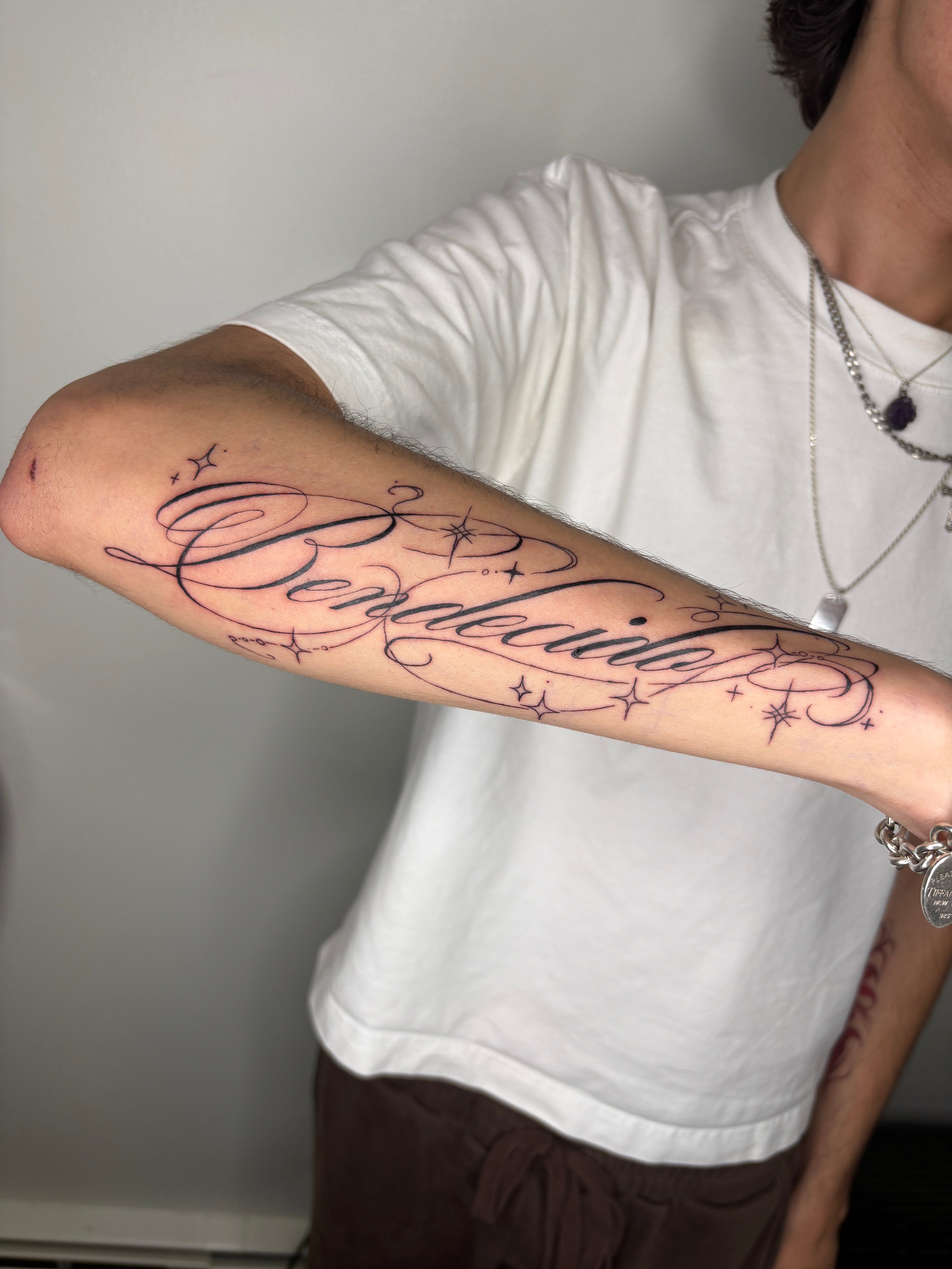 Calligraphy script text tattoo on arm 