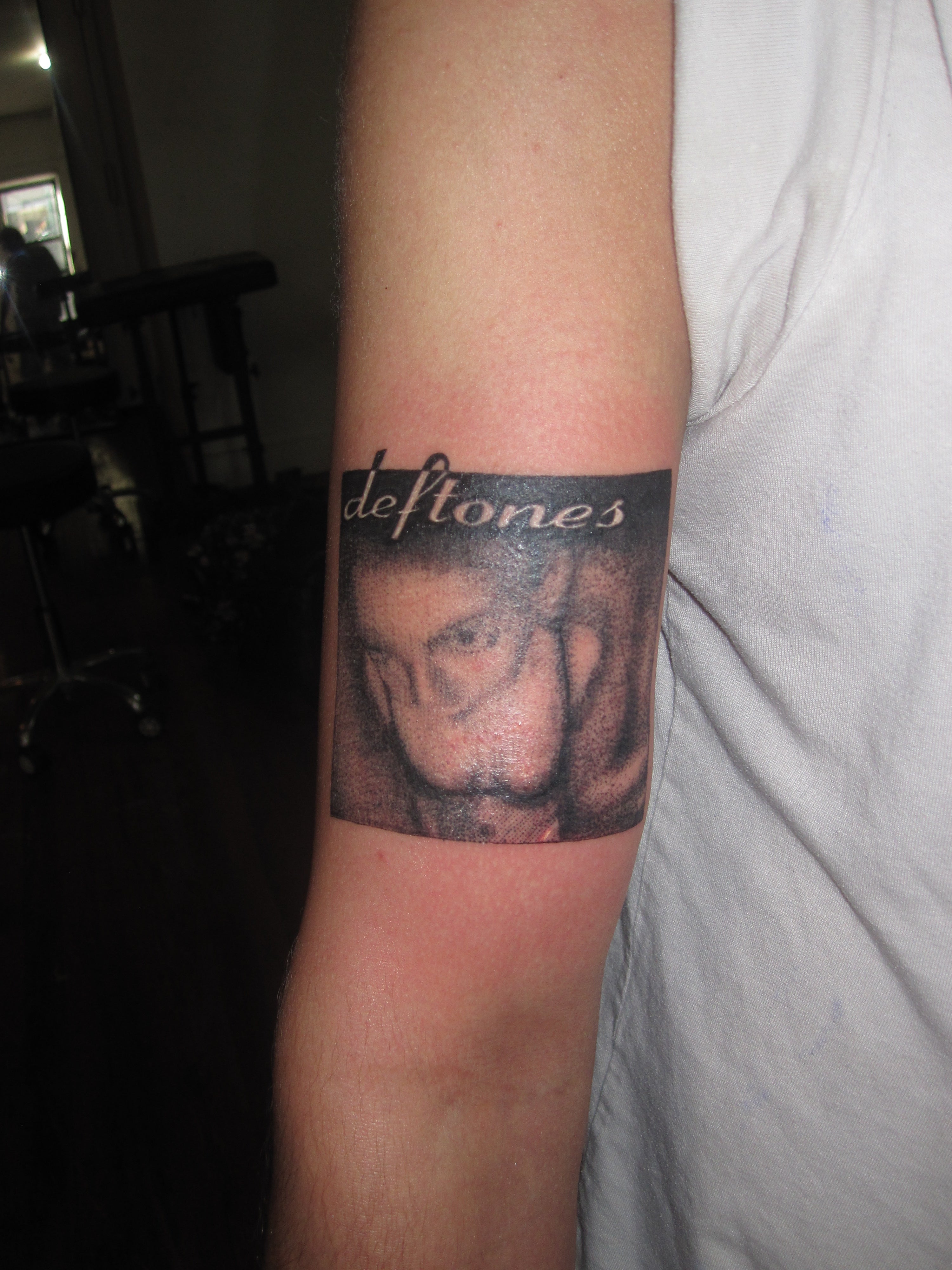 Tattoo of a face with 'deftones' around the fur album