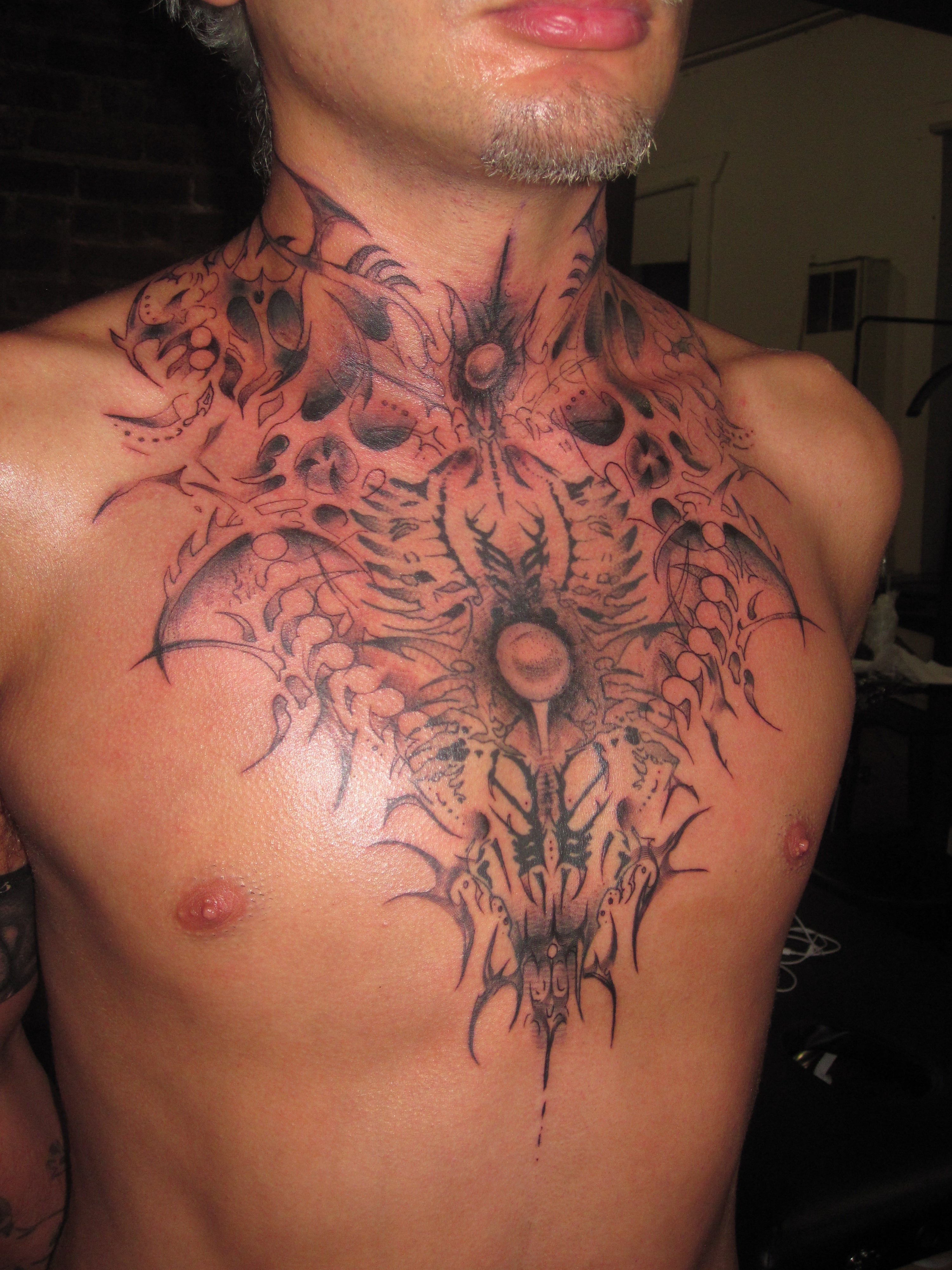 Tattoo on a person's chest with intricate cyber tribal design