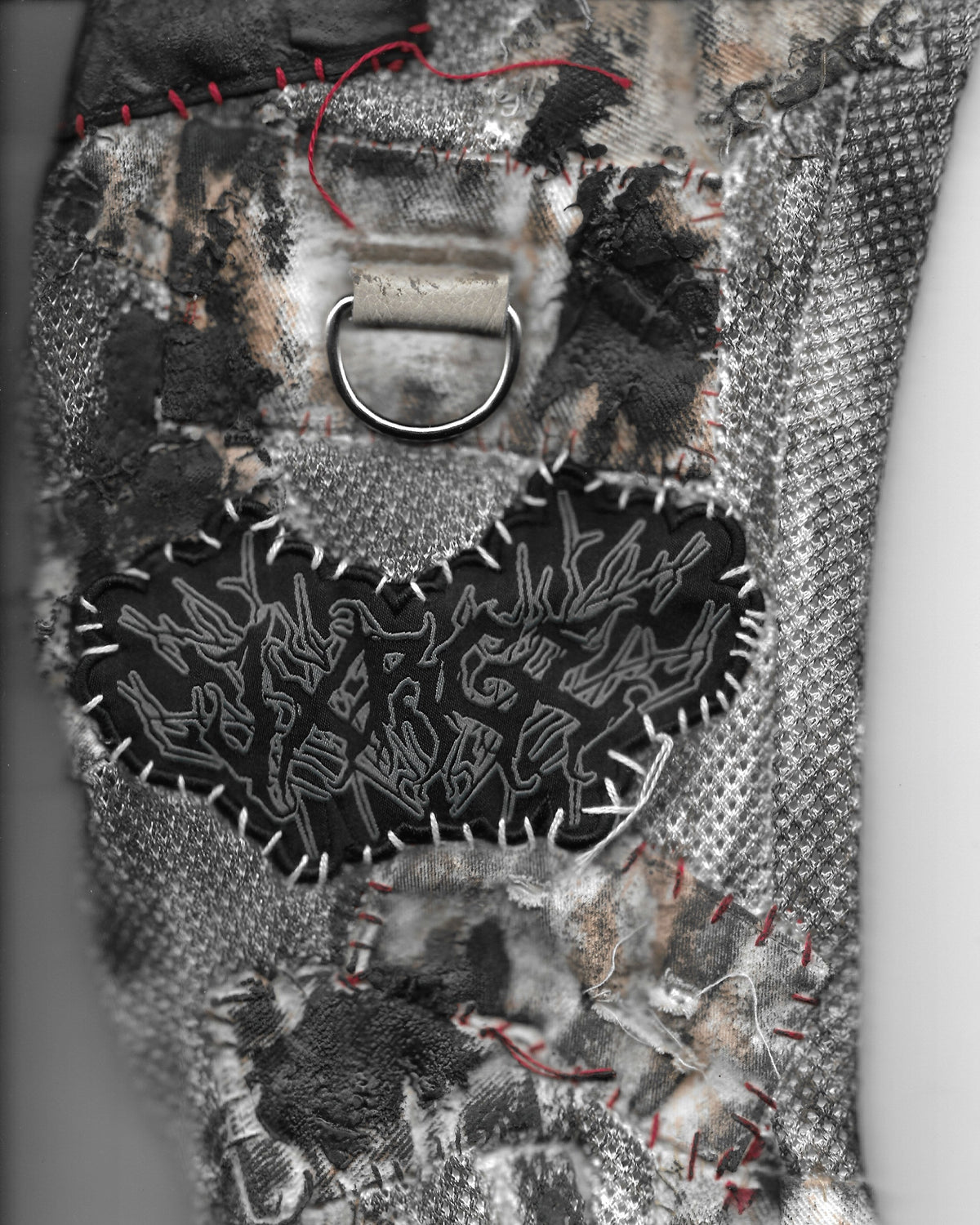 Textile art piece with embroidered text and patterns on a neutral background